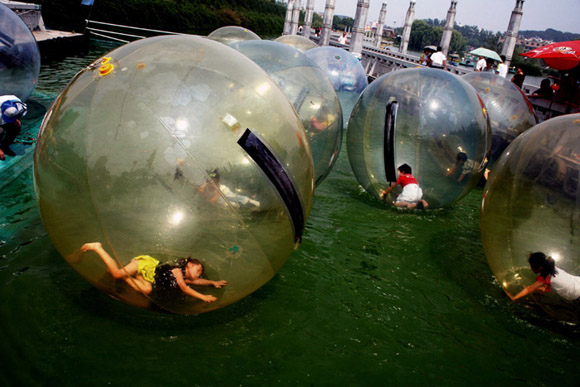 Children play in giant inflatable balls on a lake in the White Horse Sculpture Park in Nanjing, China.