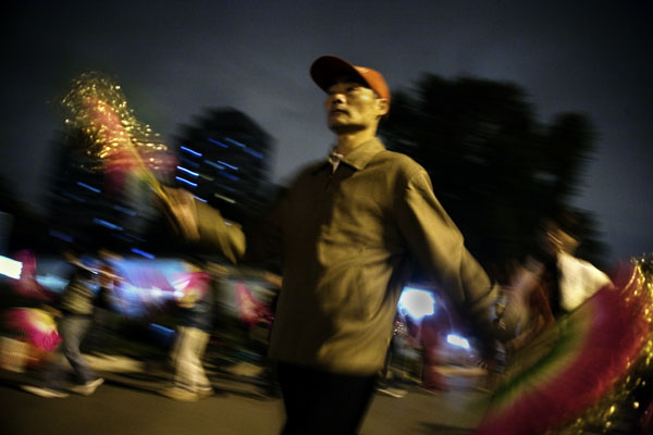 People dance with colorful folding fans on a sidewalk in Beijing, China.