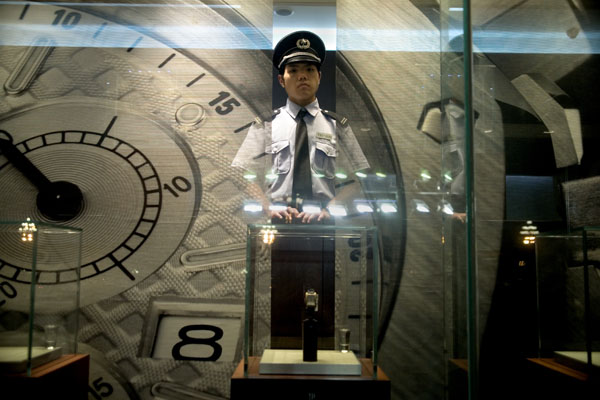 A security guard looks out of a luxury jewelry store through a window display in Beijing, China.