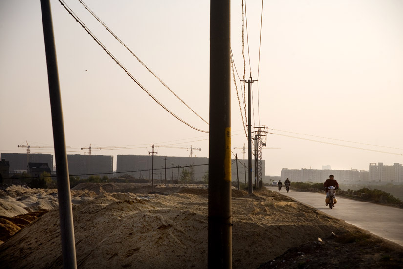 Motorscooter riders pass by construction sites in Jianging, Nanjing, Jiangsu, China.