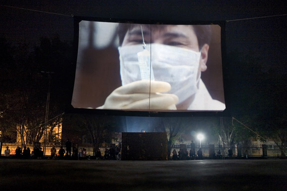 A public service film about medicine, health, and hygiene, plays on a temporary screen in a park in Hekou, Yunnan Province, China, on the Vietnam border.