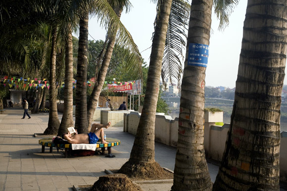 People sit in a small park along the banks of the Honghe River in Hekou, Yunnan Province, China, on the Vietnam border.  The Honghe River is also known as Hong He or the Red River.