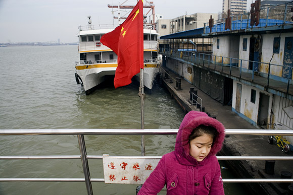 A girl rides a small passenger ferry across the Yangtze River from Nanjing to Pukou, Jiangsu, China.  The Yangtze River is known as Changjiang or Chang Jiang in Mandarin Chinese.