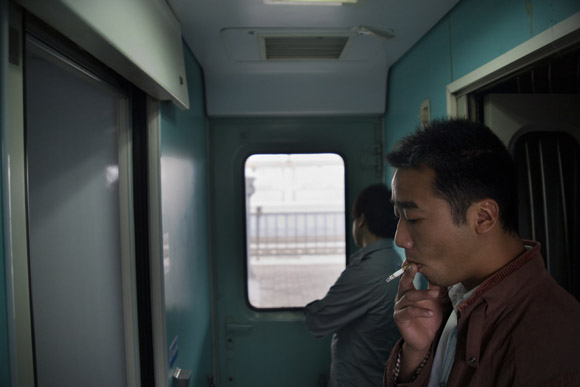 Men smoke between train cars.