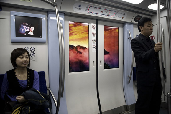 Advertisements display scenes of nature outside a subway train in Beijing, China.