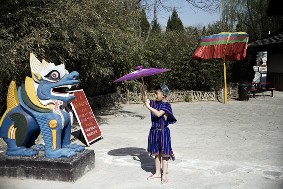A young boy plays with an umbrella in the Beijing Ethnic Minority Theme Park in Beijing, China.