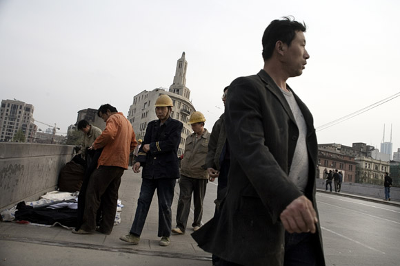 Construction workers walk past street vendors on a bridge in the Bund area of central Shanghai, China.