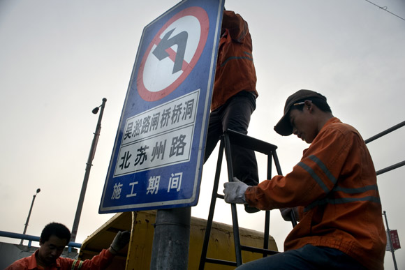 A work crew installs a new roadsign in the Bund area of central Shanghai, China.