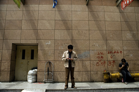 Men smoke outside of a fake designer clothing shopping mall in central Shanghai, China.