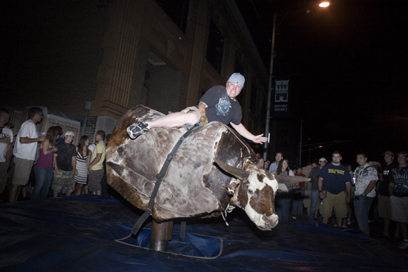 Revelers attempt to ride a mechanical bull late at night during the Evel Knievel Days festival in Butte, Montana, USA.