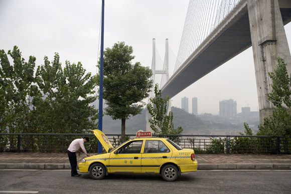 A taxi driver looks at his engine in Chongqing, China.