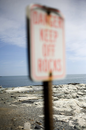 A sign warns "Danger Keep Off Rocks" at Ocean Drive State Park in Newport, Rhode Island, USA.