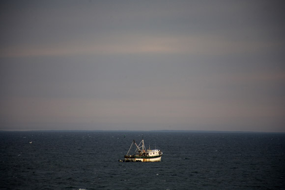 A fishing boat floats in Cape Cod Bay near Provincetown, Massachusetts, USA.