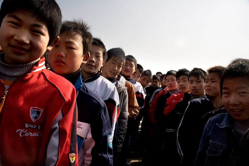 Schoolchildren gather for a school assembly on the athletic field of Yibei Middle School in Yibei Township, Guanyun County, Jiangsu Province, China.