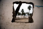 Palm trees are visible through a hole in the wall of a partially-demolished building in Sanya, Hainan, China.