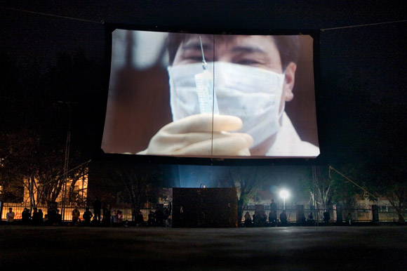A public service film about medicine, health, and hygiene, plays on a temporary screen in a park in Hekou, Yunnan Province, China, on the Vietnam border.